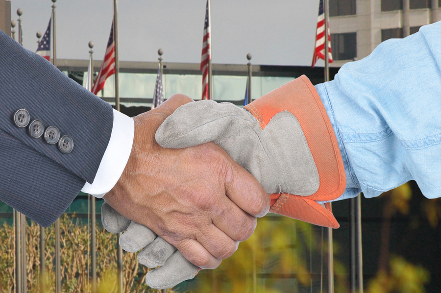 Closeup of Management and Labor handshake in front of building a