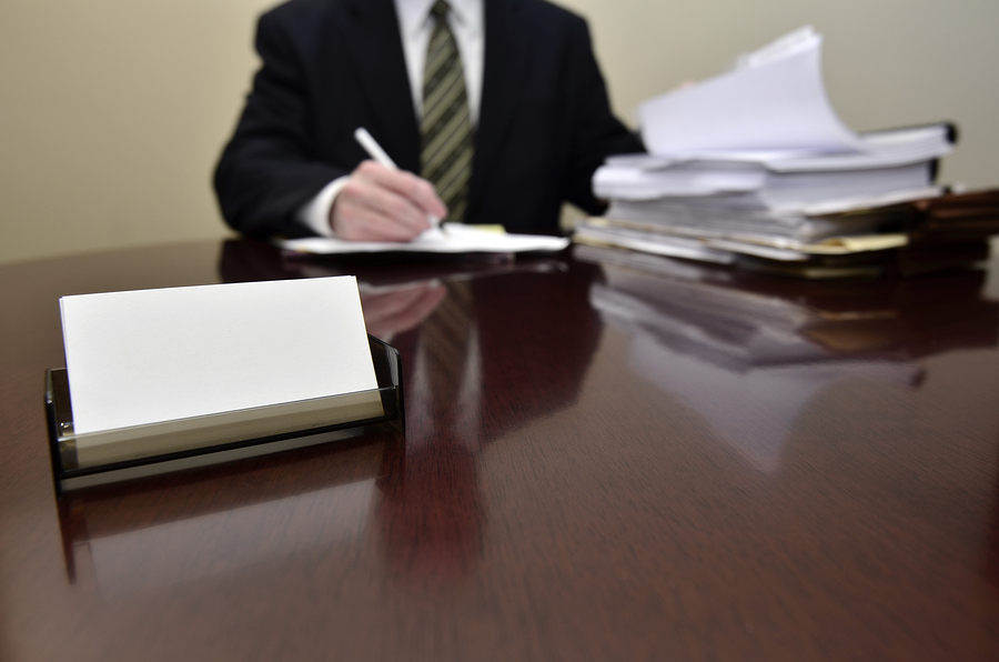 Businessman sitting at desk holding pen with files