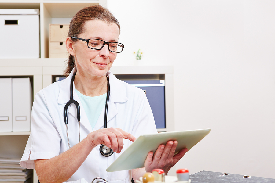 Senior female doctor using a tablet computer in her office