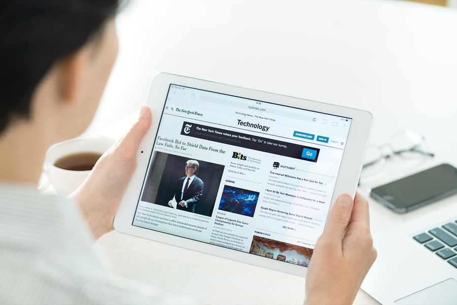 KIEV UKRAINE - JUNE 27 2014: Businesswoman reading The New York Times online article of technology news on a brand new Apple iPad Air. This website is one of America's most popular news site.