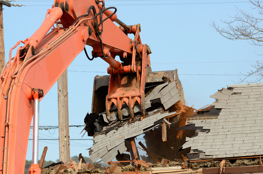 A track hoe excavator using its claw thumb to tear down an old hotel to make way for a new commercial development